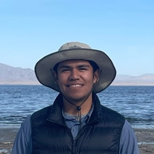 Picture of Diego Centeno, a person in a hat smiling in front of the Salton Sea